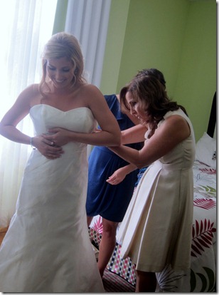 mom and sister helping into wedding gown