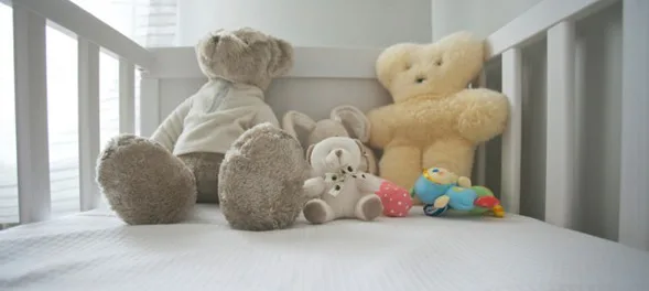 A cute crib of a baby with variety of teddies.
